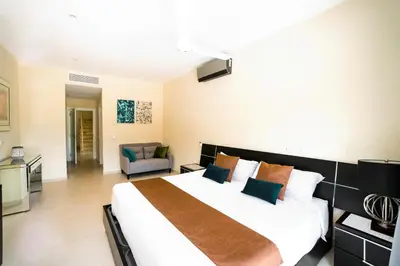 a bedroom with a large white bed and a couch at Private Iberosta Villa Fortuna - 4BDR, Pool & Private Beach in Punta Cana