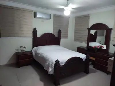 a bedroom with a large wooden bed and a mirror at Hermosa casa urbanización Jardines del Norte in Santiago de los Caballeros