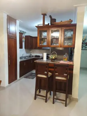 a kitchen with wooden cabinets and a table with chairs at Hermosa casa urbanización Jardines del Norte in Santiago de los Caballeros