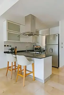 a kitchen with white cabinets and a kitchen island with chairs at Cana Rock Condos Familiar - Two apartments very close-Ground floor direct access to the pool in Punta Cana