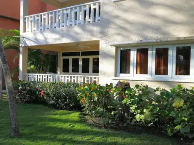 a house with a white fence and some bushes at Delightful Caribbean apartment in Boca Chica in Boca Chica