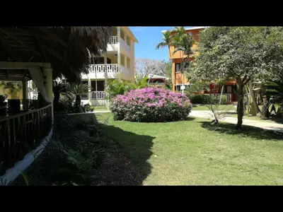 a yard with pink flowers in front of a building at Delightful Caribbean apartment in Boca Chica in Boca Chica