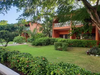a house with a green yard with bushes and trees at Delightful Caribbean apartment in Boca Chica in Boca Chica