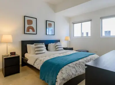 a bedroom with a large bed and two windows at Escape 3BR Apartment in the Heart of Piantini Nightlife in Santo Domingo