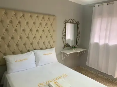 a bedroom with a white bed with a large headboard and a mirror at Glamour Hotel in La Romana