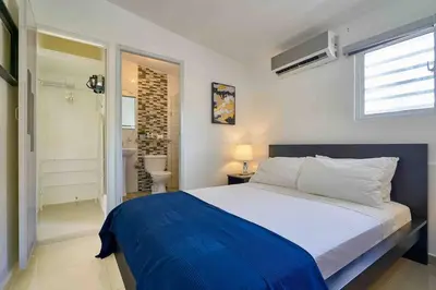 a bedroom with a large bed and a bathroom at Studio in Los Jardines Sleeps 2 in Santo Domingo
