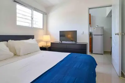 a bedroom with a large bed and a television at Studio in Los Jardines Sleeps 2 in Santo Domingo