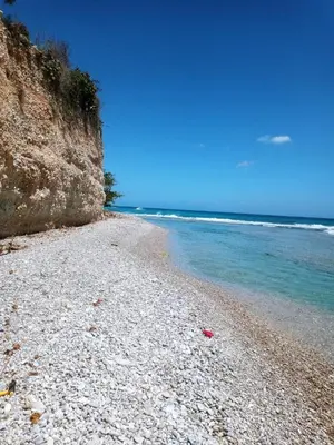 a rocky beach with blue water and a cliff at Local vacation beach house in Santa Cruz de Barahona