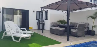 a patio with chairs and an umbrella and a pool at Townhouse with Private Pool and nearby beaches in Punta Cana