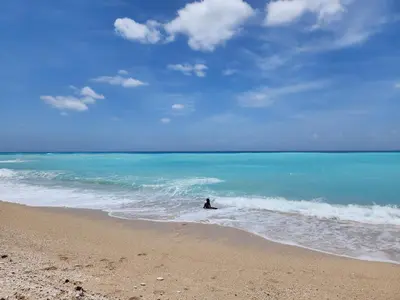 a person sitting on a surfboard in the ocean at Beachfront Apartment, Quiet 4 Beds, 1 Bath, AC, Wi-Fi, Hot Water, in Paraiso near Los Patos in Paraíso