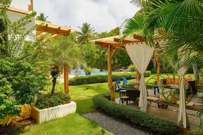 a garden with a wooden pergola and a table and chairs at Escape Beach Villa in El Portillo, Las Terrenas in Las Terrenas