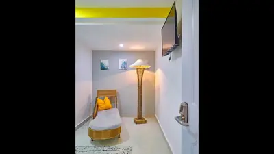 a room with a lamp and a chair and a tv at Malecon Premium Plus in Santo Domingo