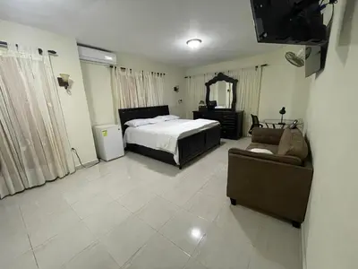 a bedroom with a bed and a couch and a television at Maria's Entire House HIGUEY 2BD in Higuey