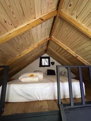 a bed in the attic of a house at Lovely tiny studio in Jarabacoa