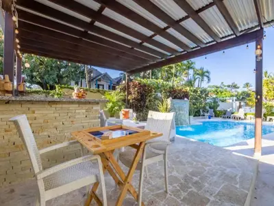 a patio with a table and chairs and a swimming pool at Stylish 1r-1b Apt Near The Beach And Main Street in Sosúa