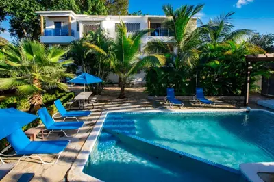a swimming pool with chairs and a house at Stylish 1r-1b Apt Near The Beach And Main Street in Sosúa
