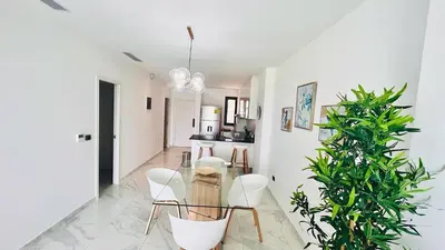 a living room with a glass table and white chairs at Luxury Apartment With Pool And Golf View in Punta Cana