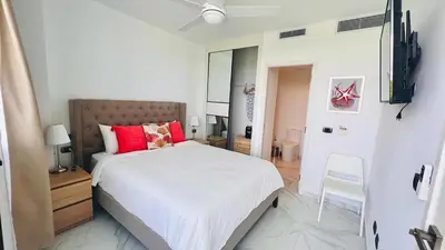 a bedroom with a large white bed with red pillows at Luxury Apartment With Pool And Golf View in Punta Cana