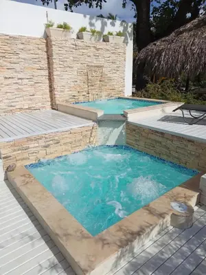 a swimming pool with a brick wall and blue water at Studio Residencial Almendra in Cabarete
