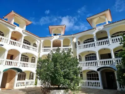 a large white building with a tree in the courtyard at Costambar in San Felipe de Puerto Plata