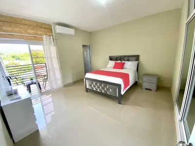 a bedroom with a bed with a red and white blanket at Balcón Skyline 2 in Jarabacoa