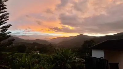 a sunset with mountains in the background and a house at Apartamento los 3B in Manabao