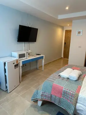 a room with two beds and a desk with a television at Noe Hotel One BedRoom #3 in Punta Cana