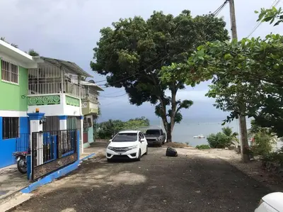 a white car parked next to a building next to the ocean at Apto 2Habitaciones con Aire y Vista al Malecón de Samaná in Santa Bárbara de Samaná