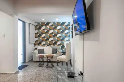 a living room with a couch and a tv on a wall at Escape 2BR Apartment in Gazcue Close to Colonial Zone in Santo Domingo