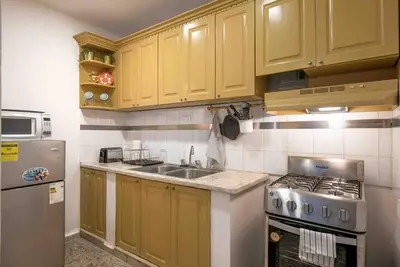 a kitchen with yellow cabinets and a sink and a stove at Escape 2BR Apartment in Gazcue Close to Colonial Zone in Santo Domingo