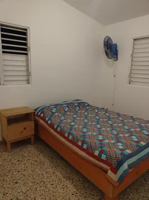 a bedroom with a bed and a table with a fan at Apart cercano al muelle y al malecón de Samana in Santa Bárbara de Samaná