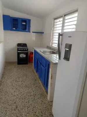a small kitchen with blue cabinets and a refrigerator at Apart cercano al muelle y al malecón de Samana in Santa Bárbara de Samaná