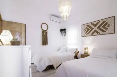 a white bedroom with two beds and a chandelier at New Beachfront Penthouse Punta Popy in Las Terrenas