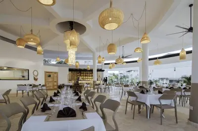 a restaurant with white tables and chairs and chandeliers at New Beachfront Penthouse Punta Popy in Las Terrenas