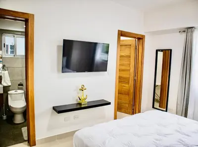 a bedroom with a bed and a toilet and a television at Super Luxurious L6 Sky Blue Apartment in Santo Domingo