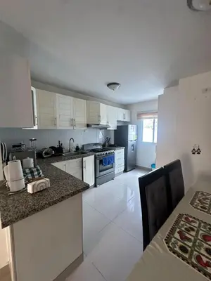 a kitchen with white cabinets and a table and a counter top at Residencial selene V, Family Modern Apartment w Pool & Near the beach in Punta Cana