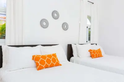 two white beds with orange pillows in a room at Sosua Ocean Village Properties by Calisto Stays in Sosúa