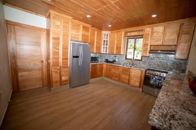 a kitchen with wooden cabinets and a stainless steel refrigerator at ωιℓℓу'ѕ νιℓℓα in Jarabacoa