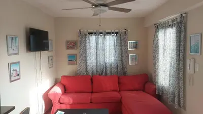 a red couch in a living room with a ceiling fan at Casa Kamanda, Zona Colonial, Santo Domingo in Santo Domingo