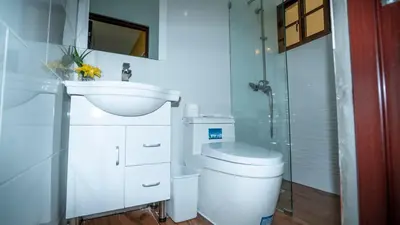 a white bathroom with a toilet and a sink at Peace By The River in Jarabacoa