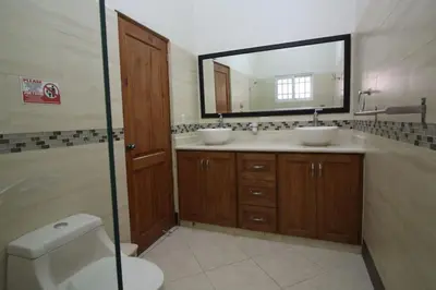 a bathroom with two sinks and a mirror and a toilet at Super Spacious 4BR 4 5BA Villa w pool in Sosua in Sosúa