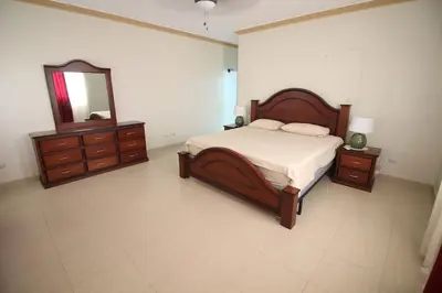 a bedroom with a bed and a dresser and a mirror at Super Spacious 4BR 4 5BA Villa w pool in Sosua in Sosúa