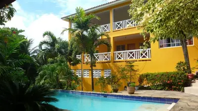 a yellow house with a swimming pool in front of it at Costambar Tropical Garden in San Felipe de Puerto Plata