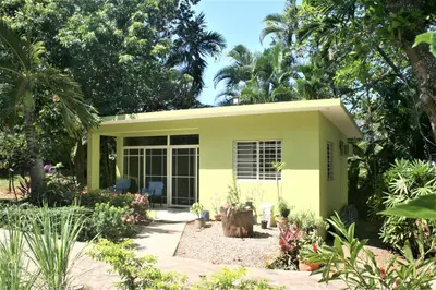 a yellow house with a garden in front of it at Costambar Tropical Garden in San Felipe de Puerto Plata