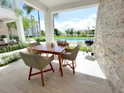 a patio with a wooden table and chairs at Spectacular Apto Pool Golf View in Hard Rock Golf in Punta Cana