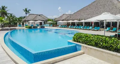 a swimming pool at a resort with chairs and umbrellas at Hard Rock Golf Cozy 1BR • Pool & Golf Views in Punta Cana
