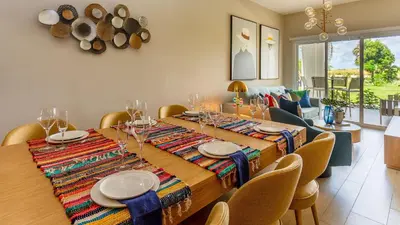 a dining room with a long wooden table with chairs at Luxury Condo with Golf Cart Included in Cana Pearl in Punta Cana