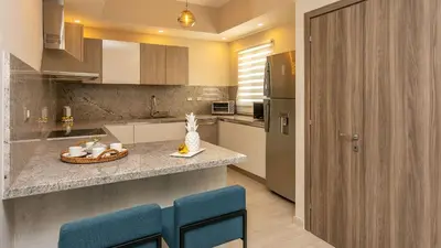 a kitchen with a counter and some blue chairs at Luxury Condo with Golf Cart Included in Cana Pearl in Punta Cana