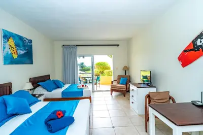 a bedroom with two beds and a desk and a table at Agualina Kite Hotel Oceanfront Apartments in Cabarete