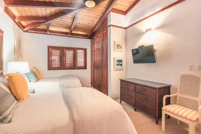 a bedroom with two beds and a flat screen tv at Fun in the sun classic villa at Los Lagos in Casa de Campo in Cajuiles